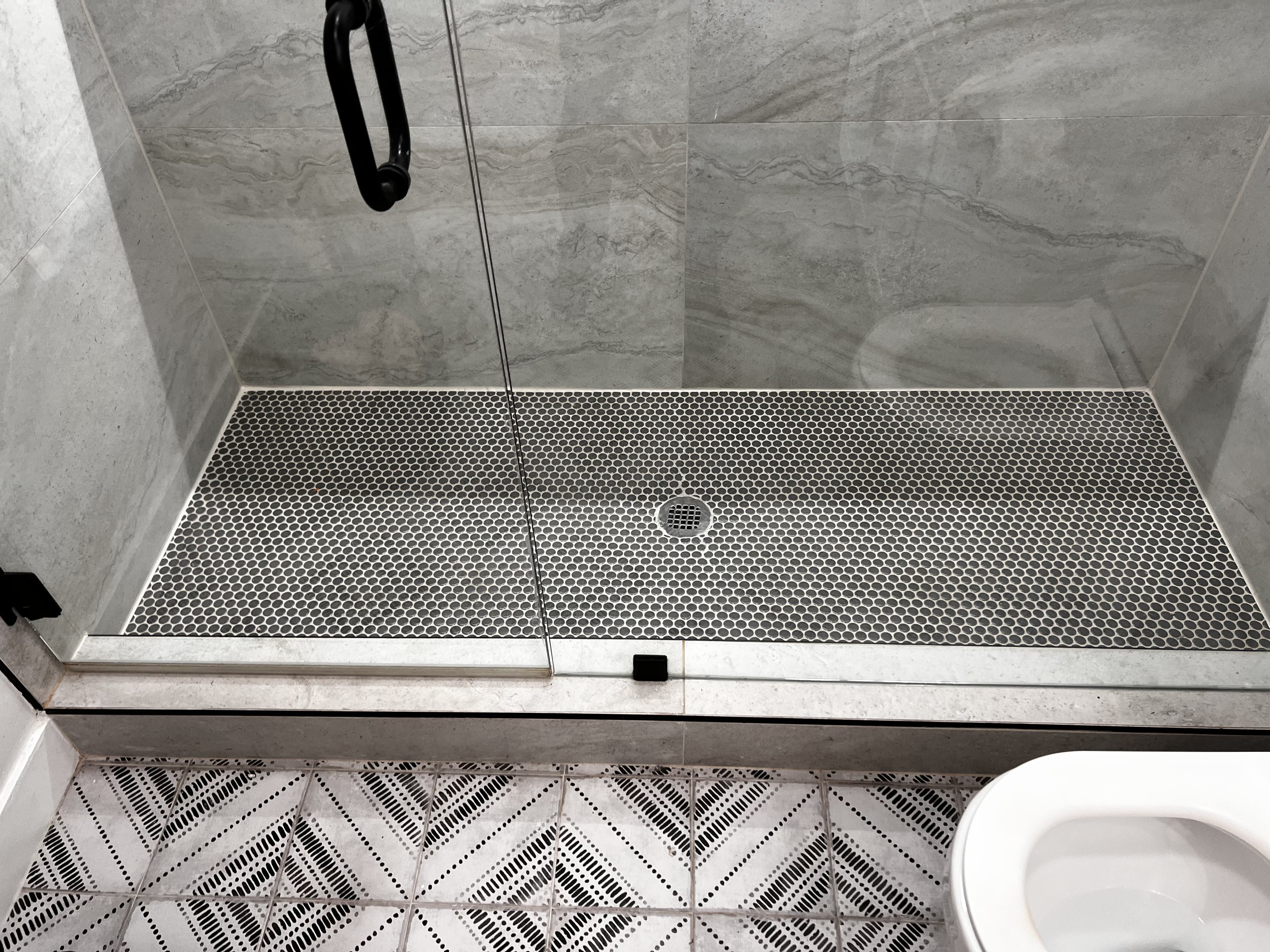 Shower with penny tile floor and geometric bathroom flooring